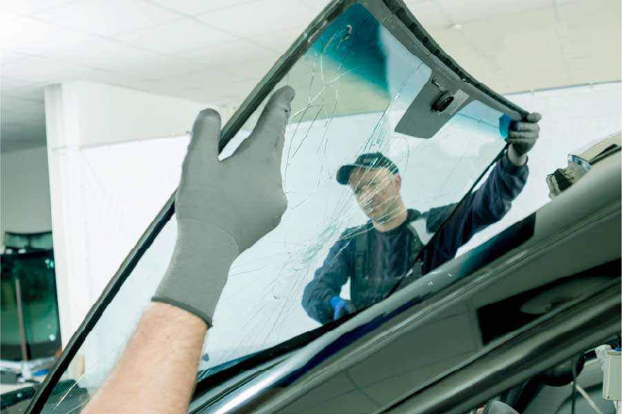 Técnicos removiendo un parabrisas dañado de un vehículo en un taller especializado.